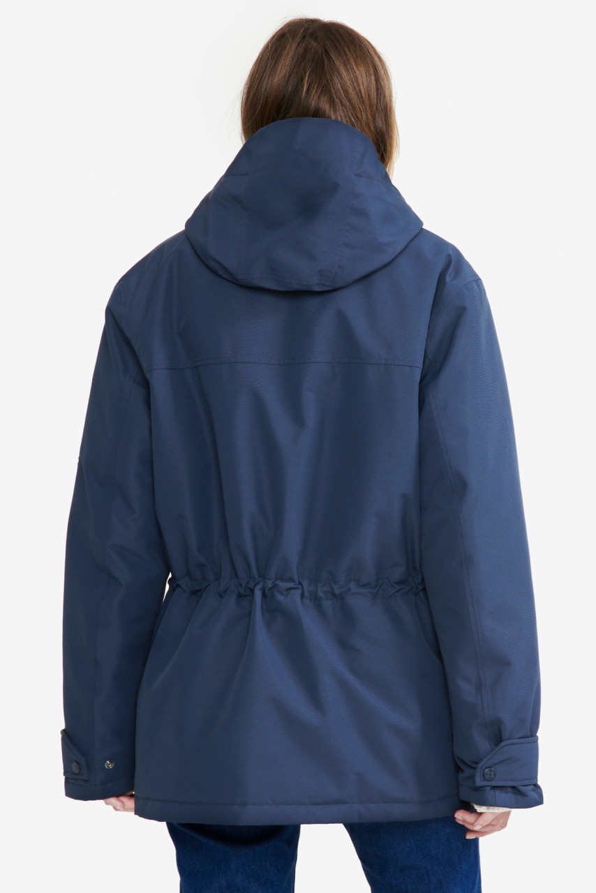 Frau trägt eine Regenjacke blau von Aigle - Rückansicht