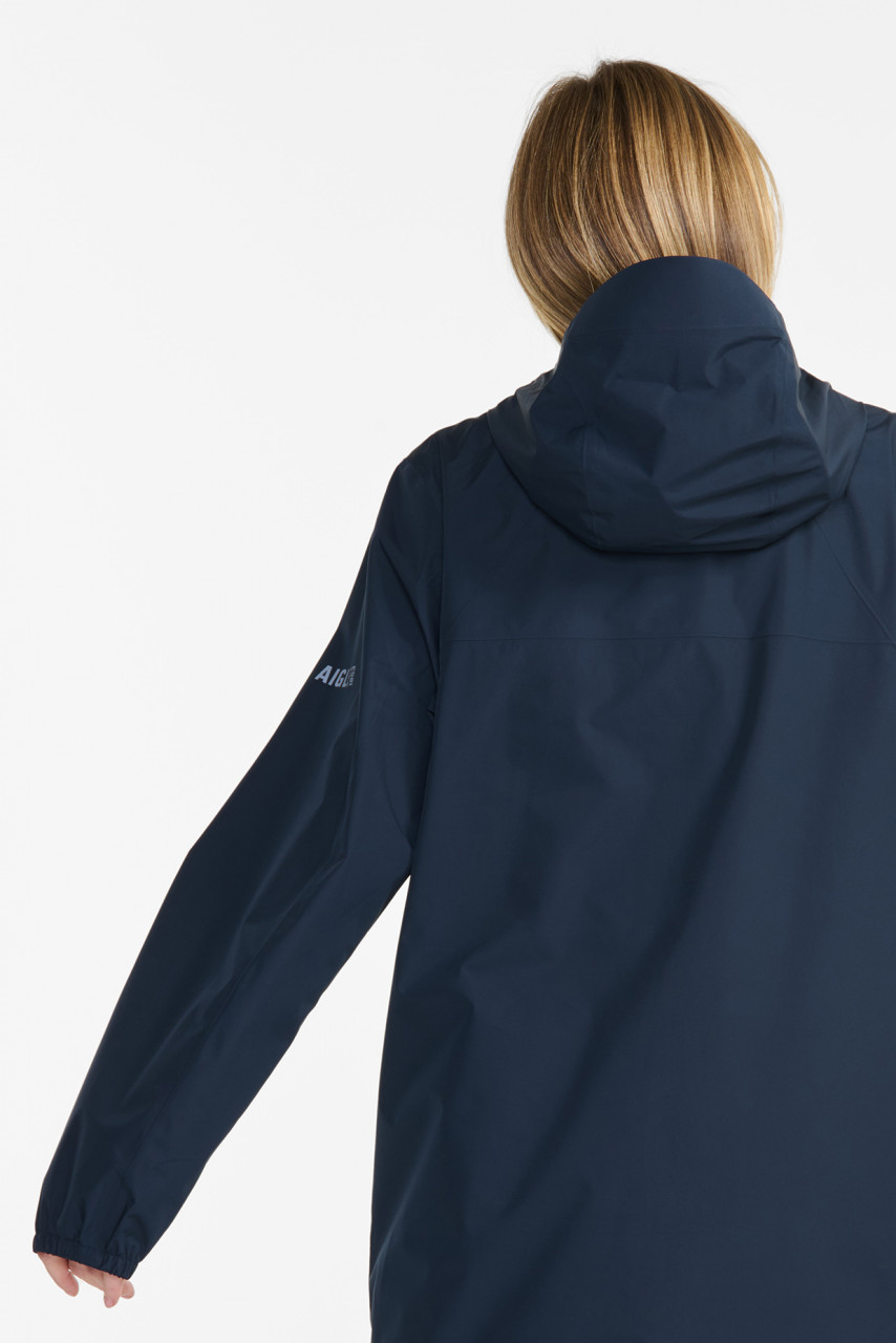 Weibliches Model trägt eine Regenjacke blau von Aigle  - Rückansicht