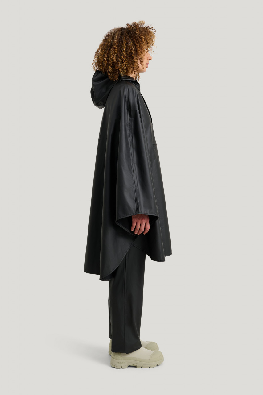 Weibliches Model trägt ein schwarzes Regenponcho Unisex von Tretorn - Seitlich