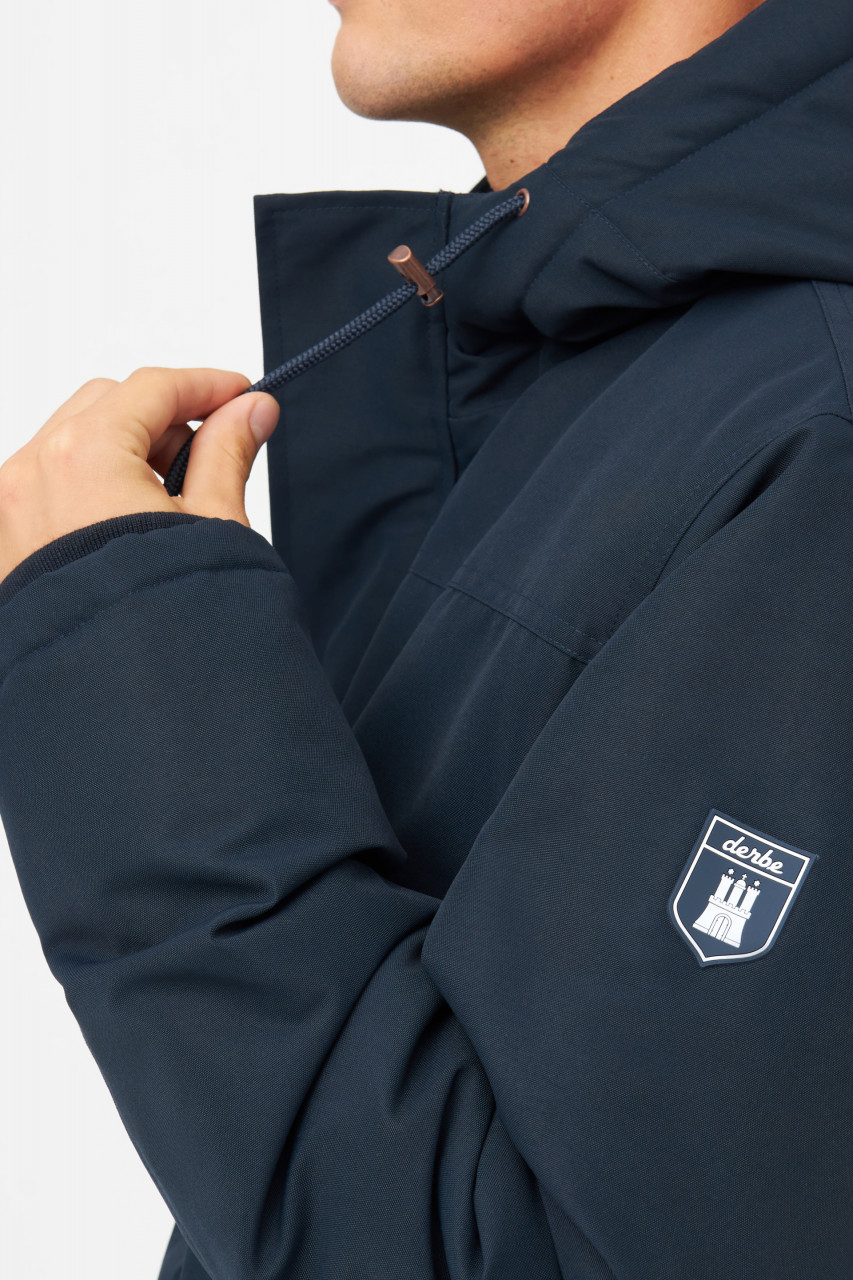 Model trägt eine blauen Winterjacke Herren von derbe - Seitlich
